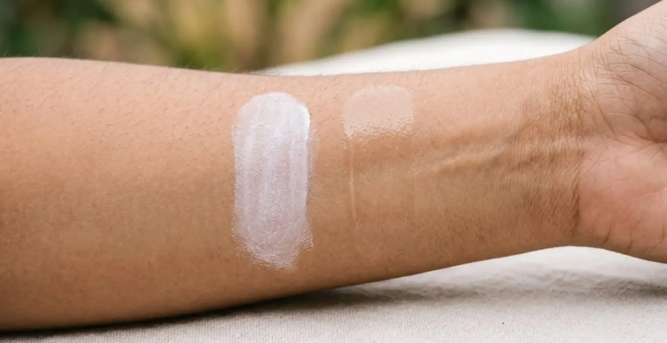 Two swatches of sunscreen texture on forearm skin — one mineral with slight white cast, one chemical with transparent finish — illustrating filter type comparison